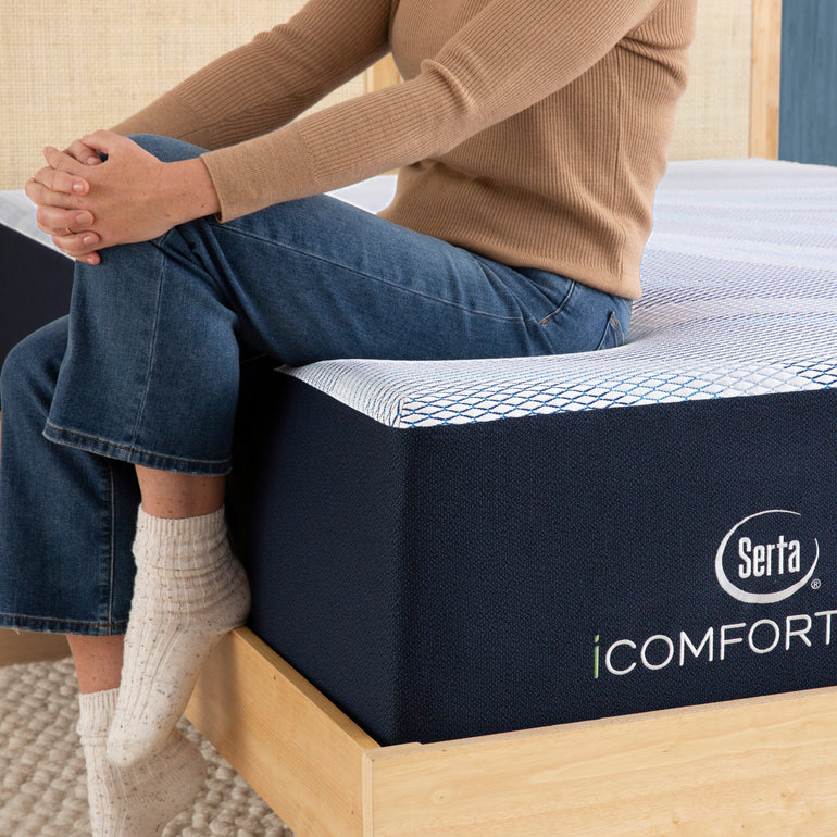 Person sitting on bed to showcase firmness level of Serta iComforteco mattress||level: ultimate