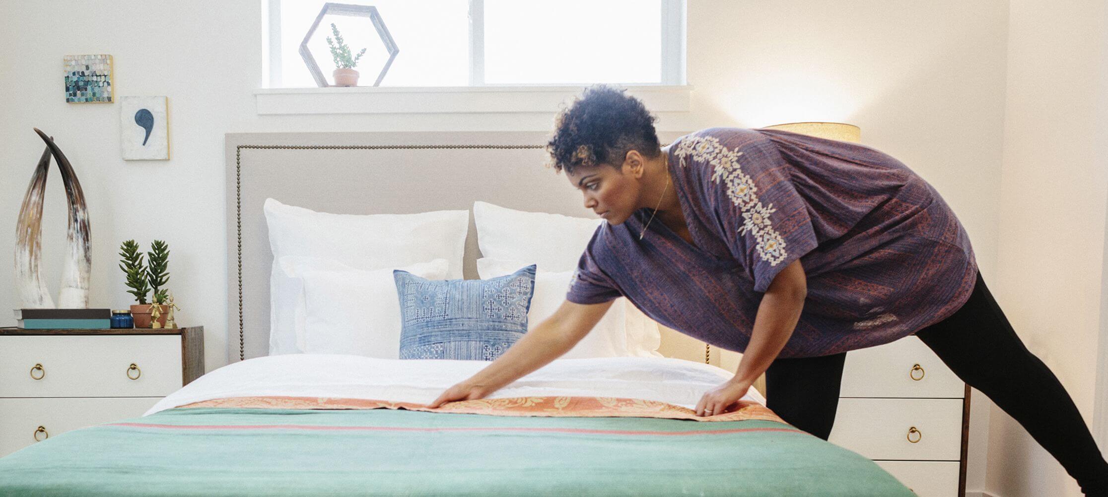 Person making bed in modern bedroom