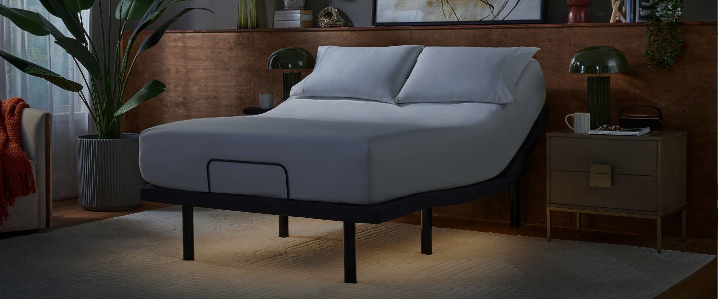 Serta mattress sitting baselogic adjustable frame with 2 pillows on top of it.