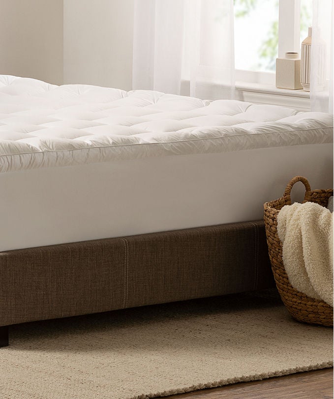 Serta mattress pad on top of a Serta mattress sitting in a brown bed frame.