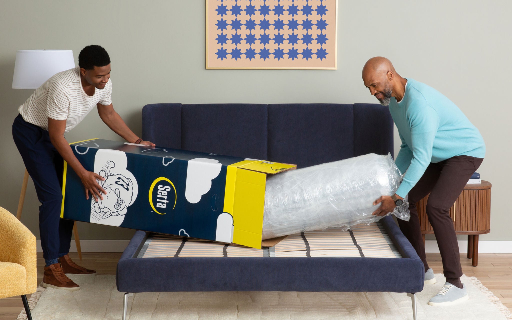 Two men unboxing a Serta mattress from the box.