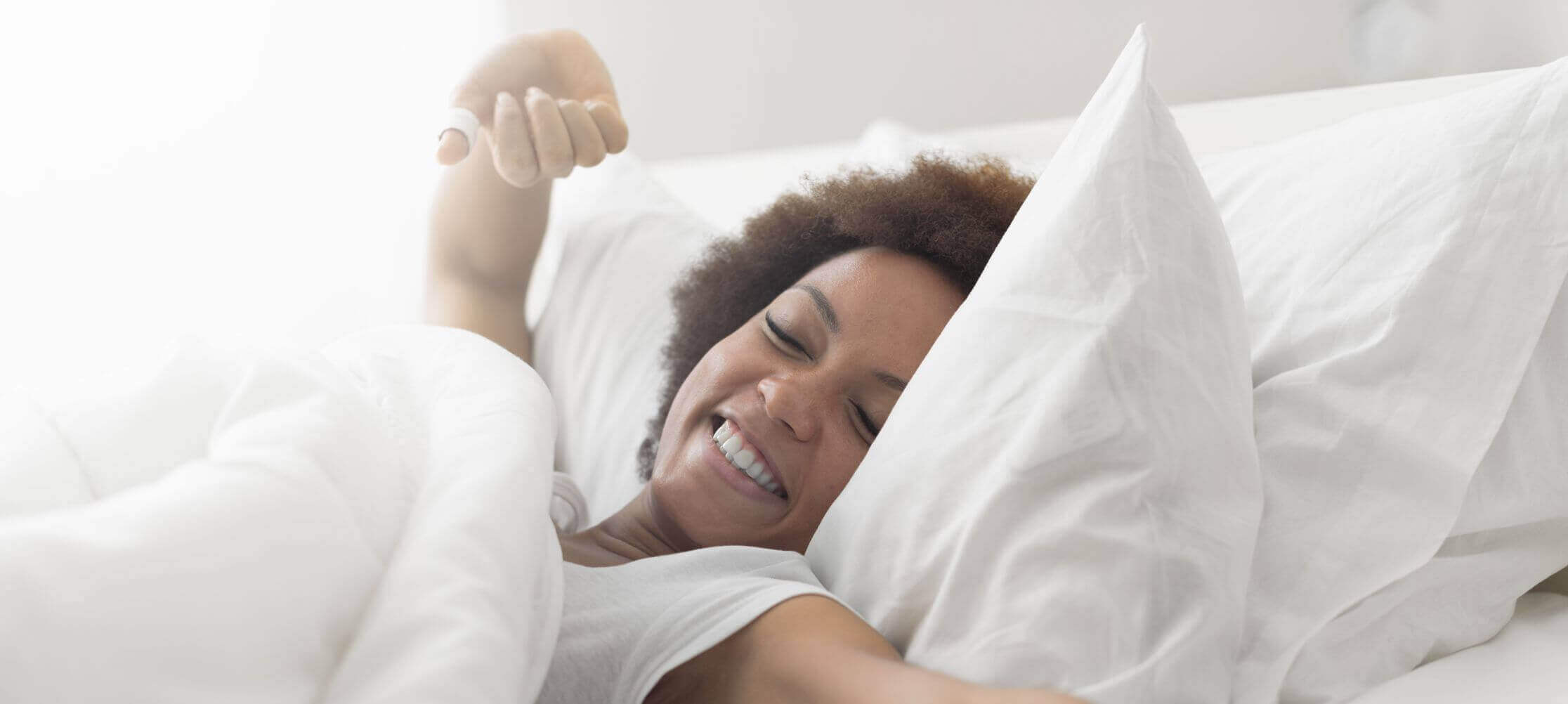 Woman waking up in white bedding