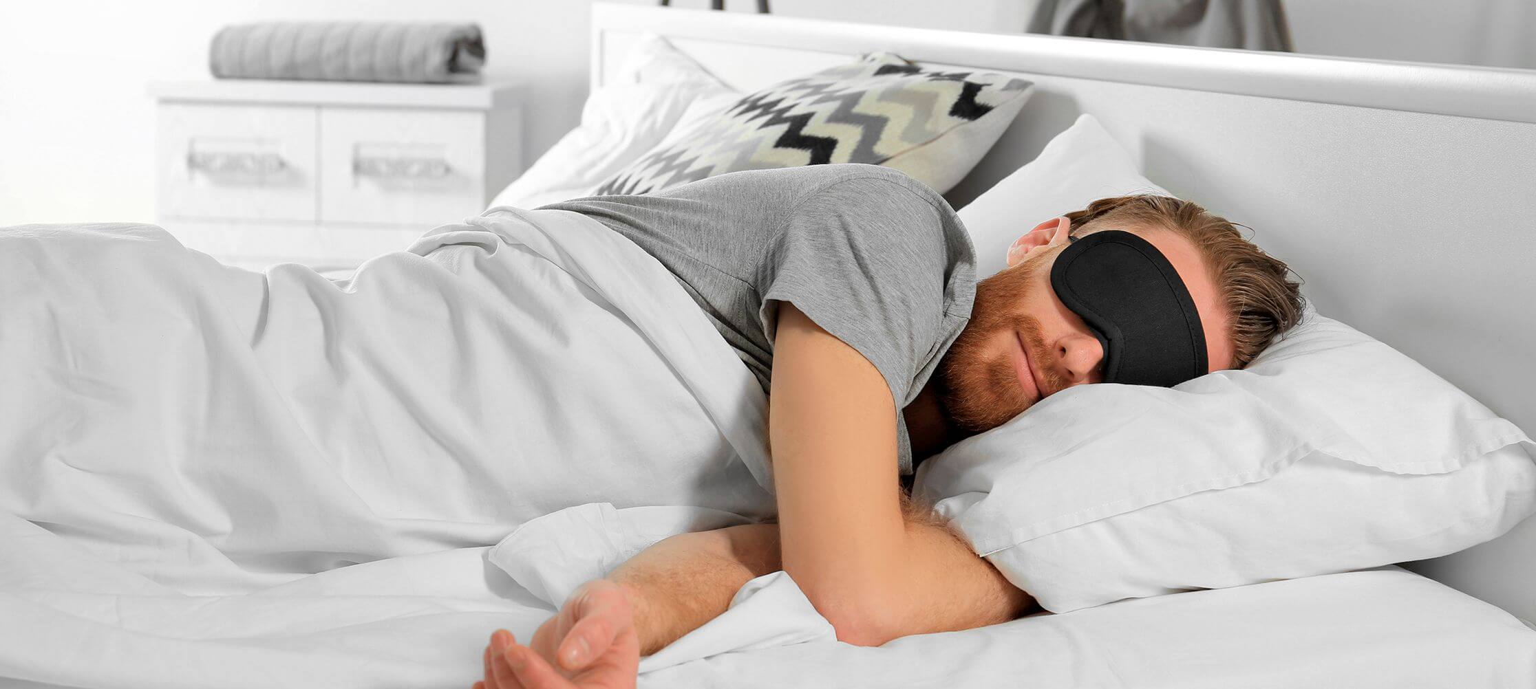 Man sleeping with black eye mask in bed
