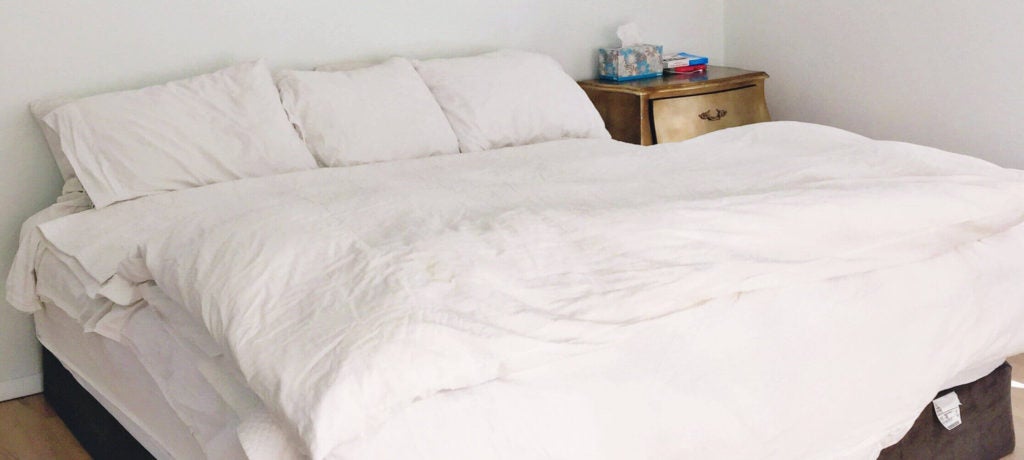 Cozy white bed with wooden nightstand