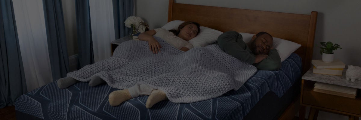 Man and woman laying on a Serta mattress asleep