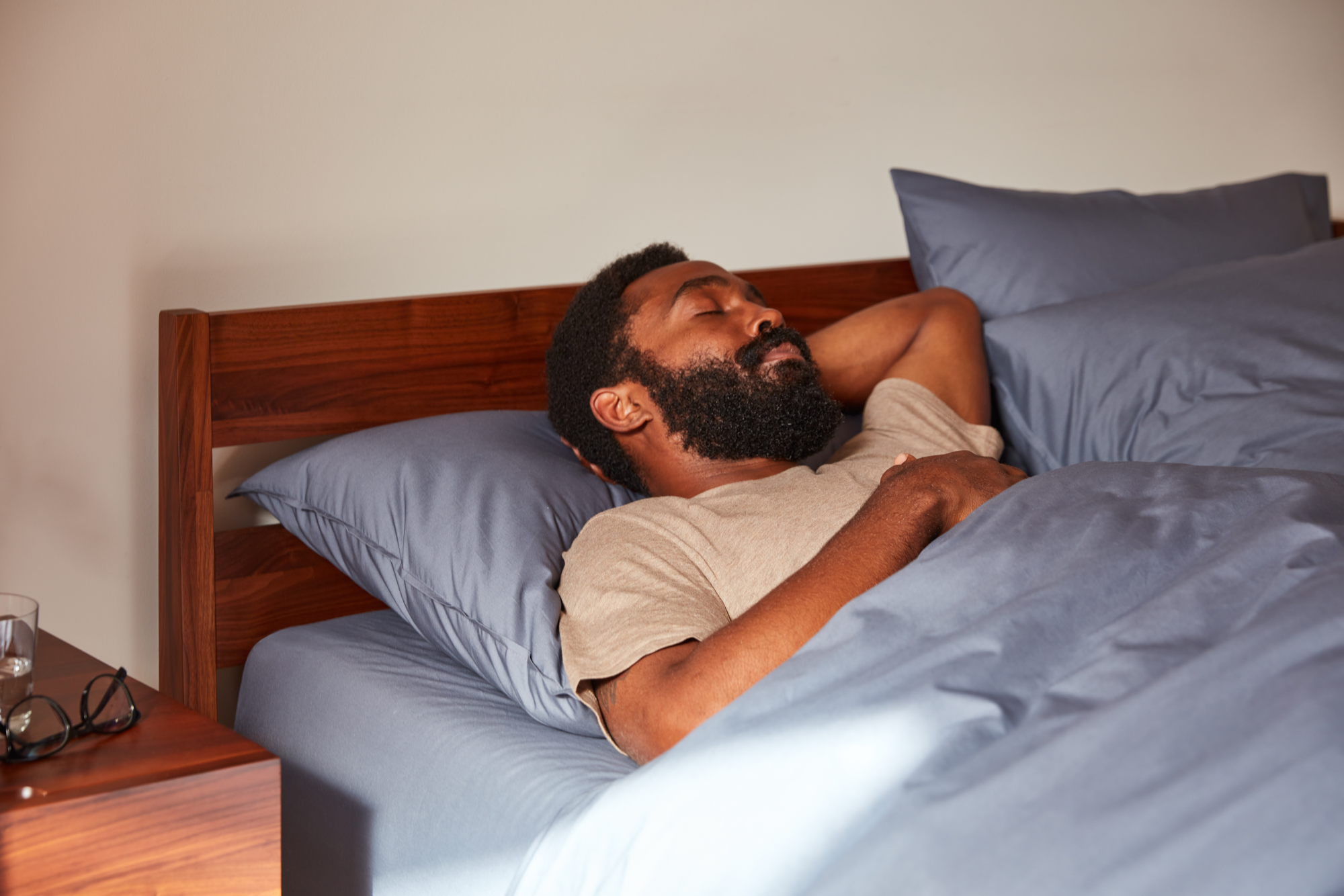 Man resting in bed with blue sheets