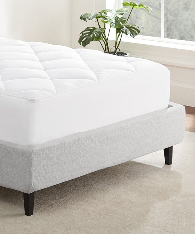 Serta mattress protector on top of a Serta mattress sitting in a gray bed frame.