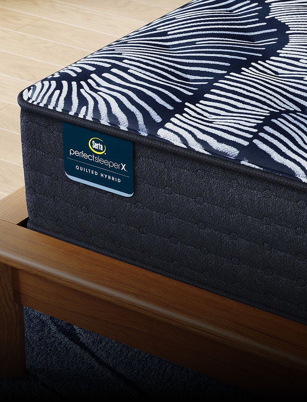 Corner of a Serta Perfect Sleeper X mattress in a brown bed frame