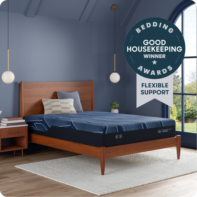 Serta iSeries NXG mattress sitting in a brown wood bedframe with 2 pillows on top of it. With a "Bedding Winner Good Housekeeping Winner Flexible Support" Circular stamp in the top right corner