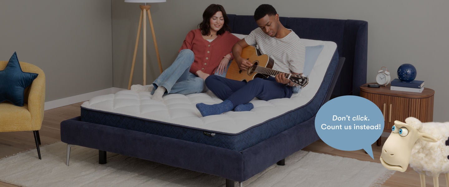 A woman and man sitting on a Serta mattress elevated on an adjustable base. The man is playing a guitar and the woman watching. A Serta sheep on the bottom right with a caption stating Don't click. Count us instead!