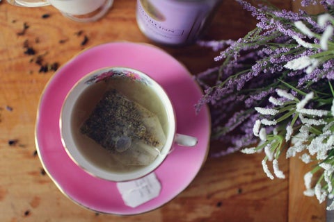 Pink teacup with herbal tea and lavender