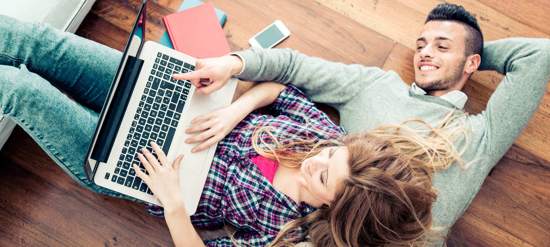 Couple relaxing with laptop on floor