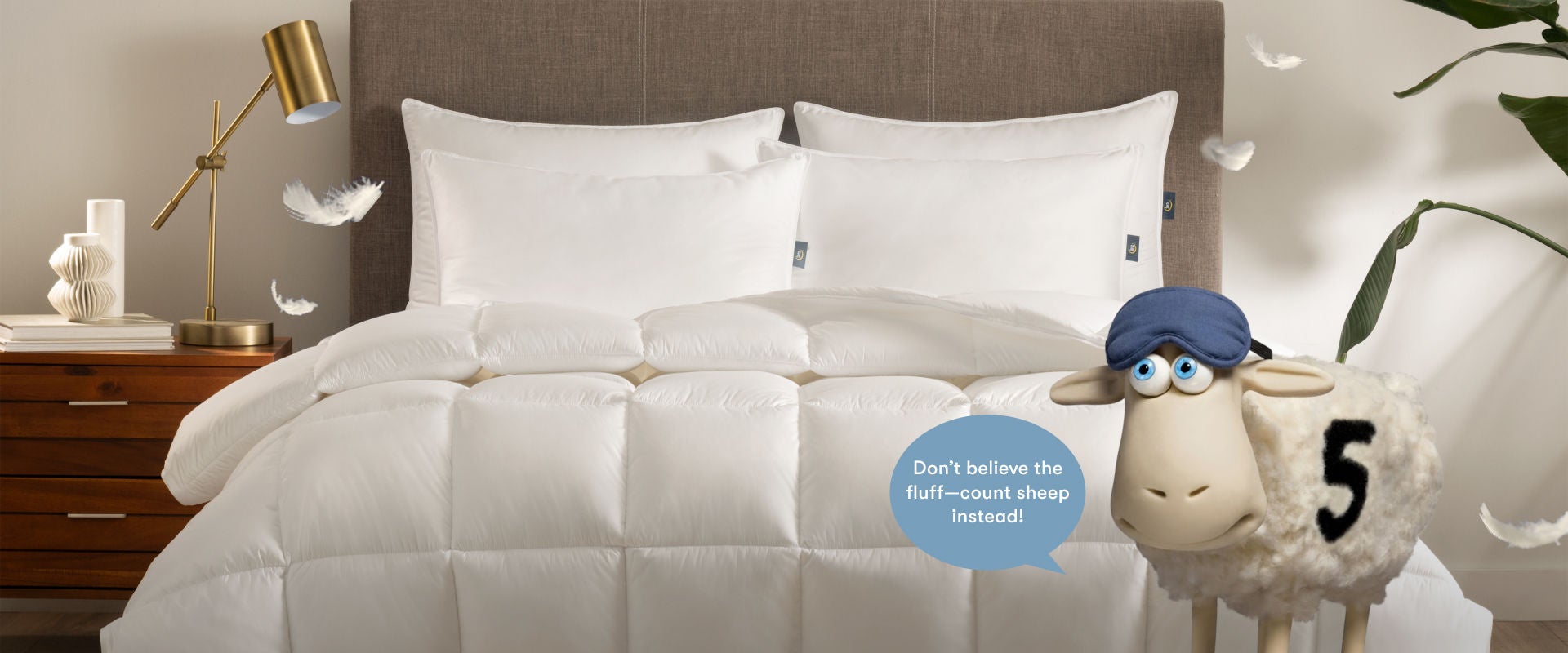 Serta comforter and 4 pillows on top of a serta mattress with the Serta sheep at the foot of the bed with a caption stating Dont believe the fluff-count sheep instead.