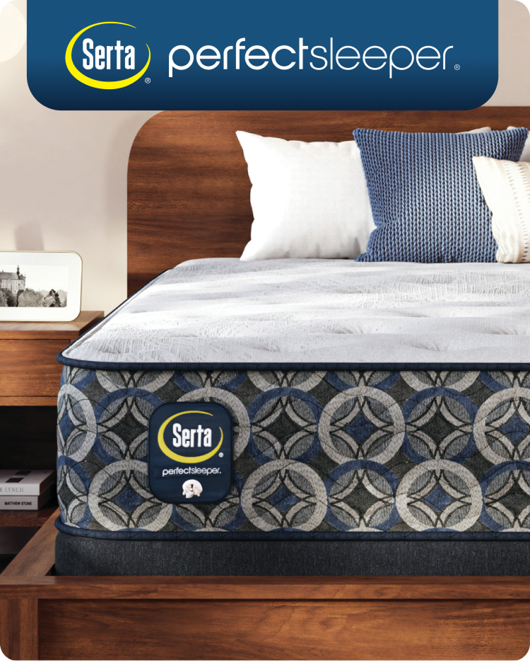 Corner of a Serta Perfect Sleeper mattress in a brown bedframe with 3 pillows on top of it.
