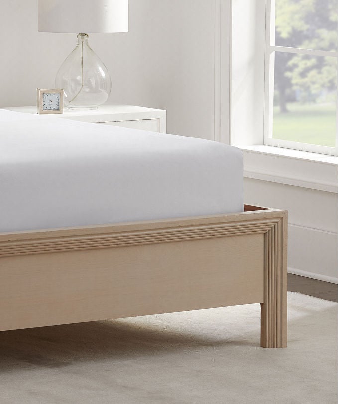 Serta mattress protector wrapped on a Serta mattress sitting in a brown bed frame.