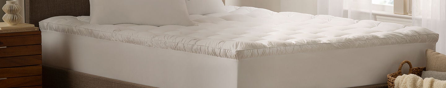 Serta mattress topper on top of a Serta mattress sitting in a brown bedframe