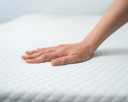 Woman’s hand placed gently on the top of a crisp white mattress.