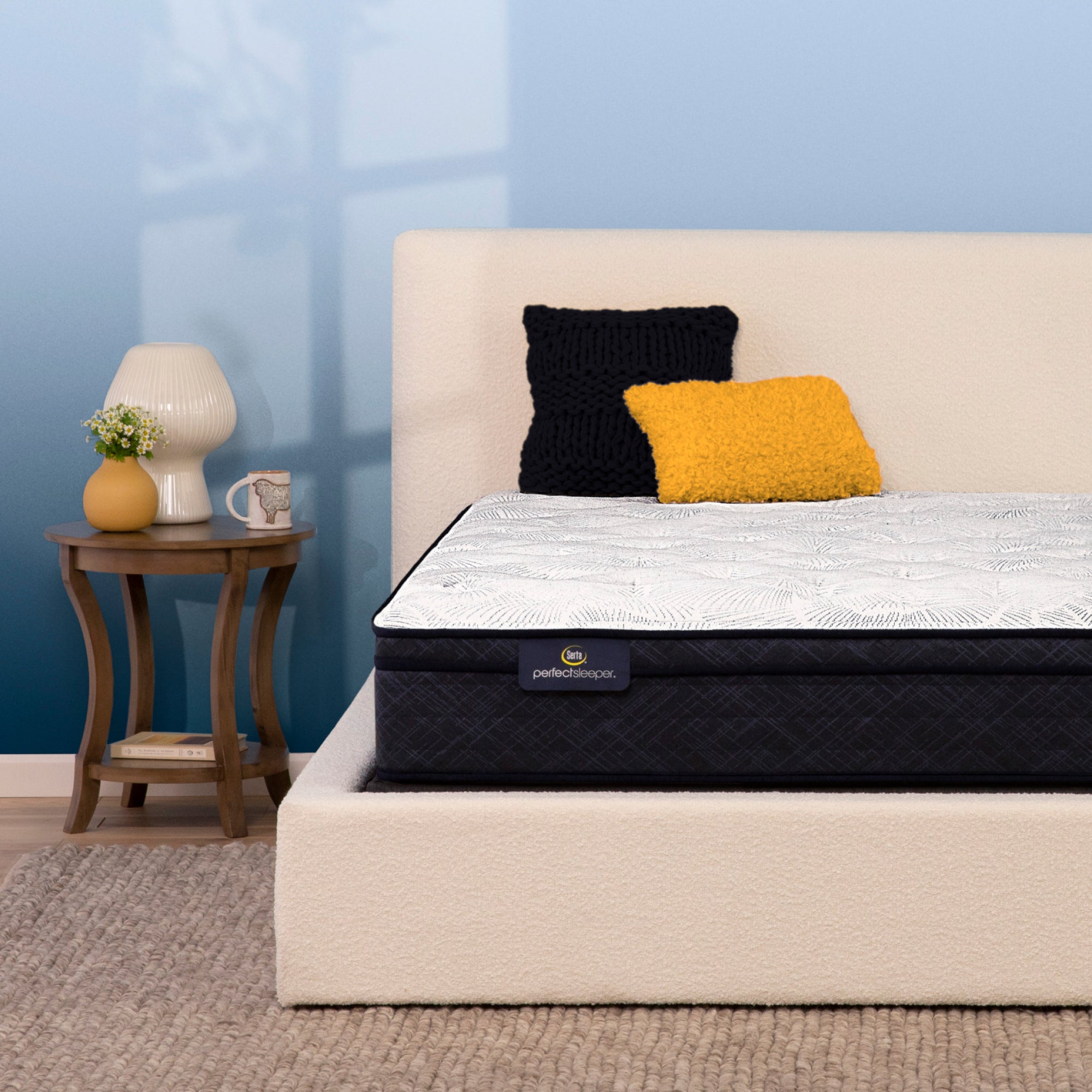 Serta Perfect Sleeper mattress on a modern upholstered bed with a cozy bedside setup.