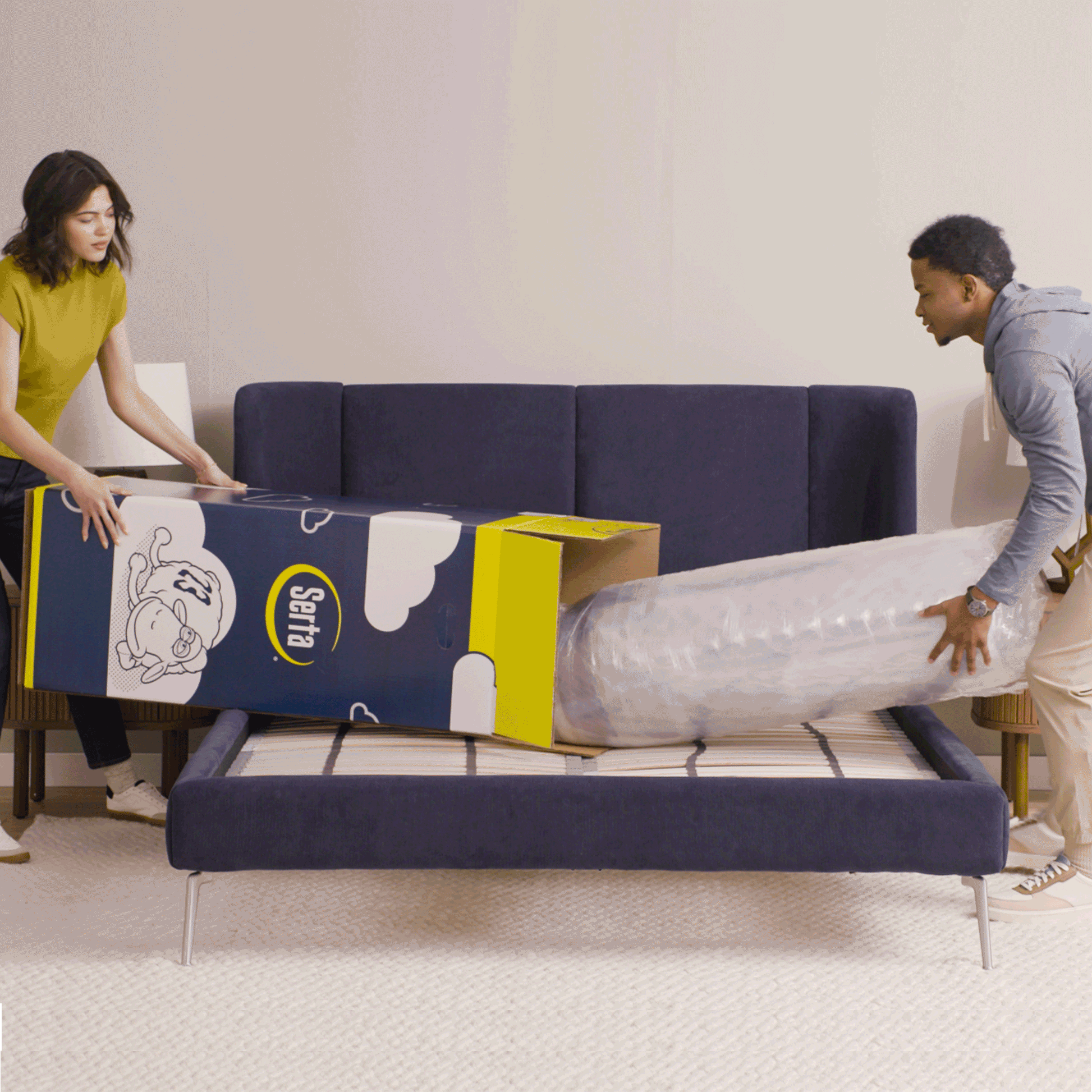 Gif video of a couple opening a mattress in a box, unrolling it and then laying on it.