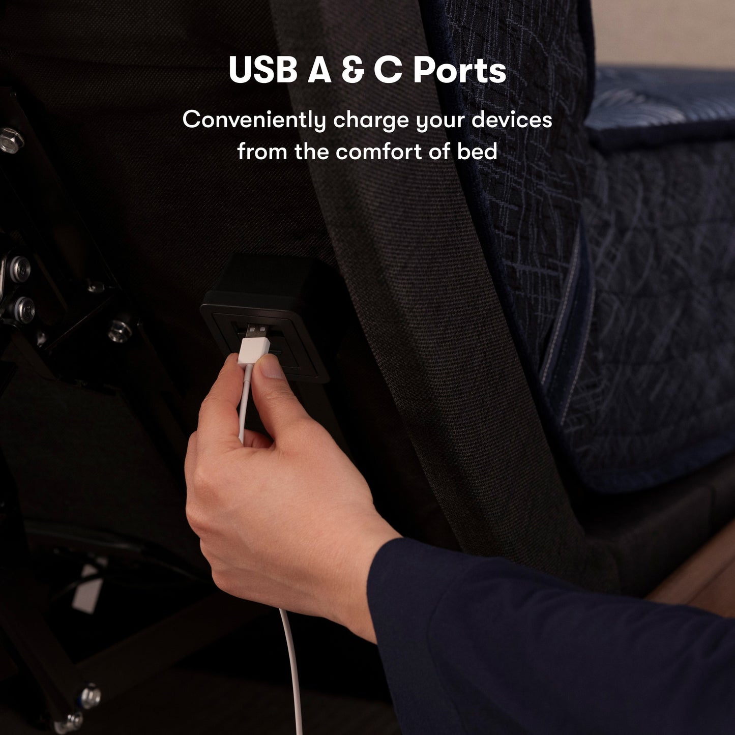 A hand of a female plugging a power cord into the back of the USB port on the back of the adjustable base. 