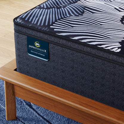 Corner of Perfect Sleeper X Quilted Hybrid Max Plush Pillow Top Mattress sitting in a brown bedframe || feel: Plush Pillow Top || level: Level 2