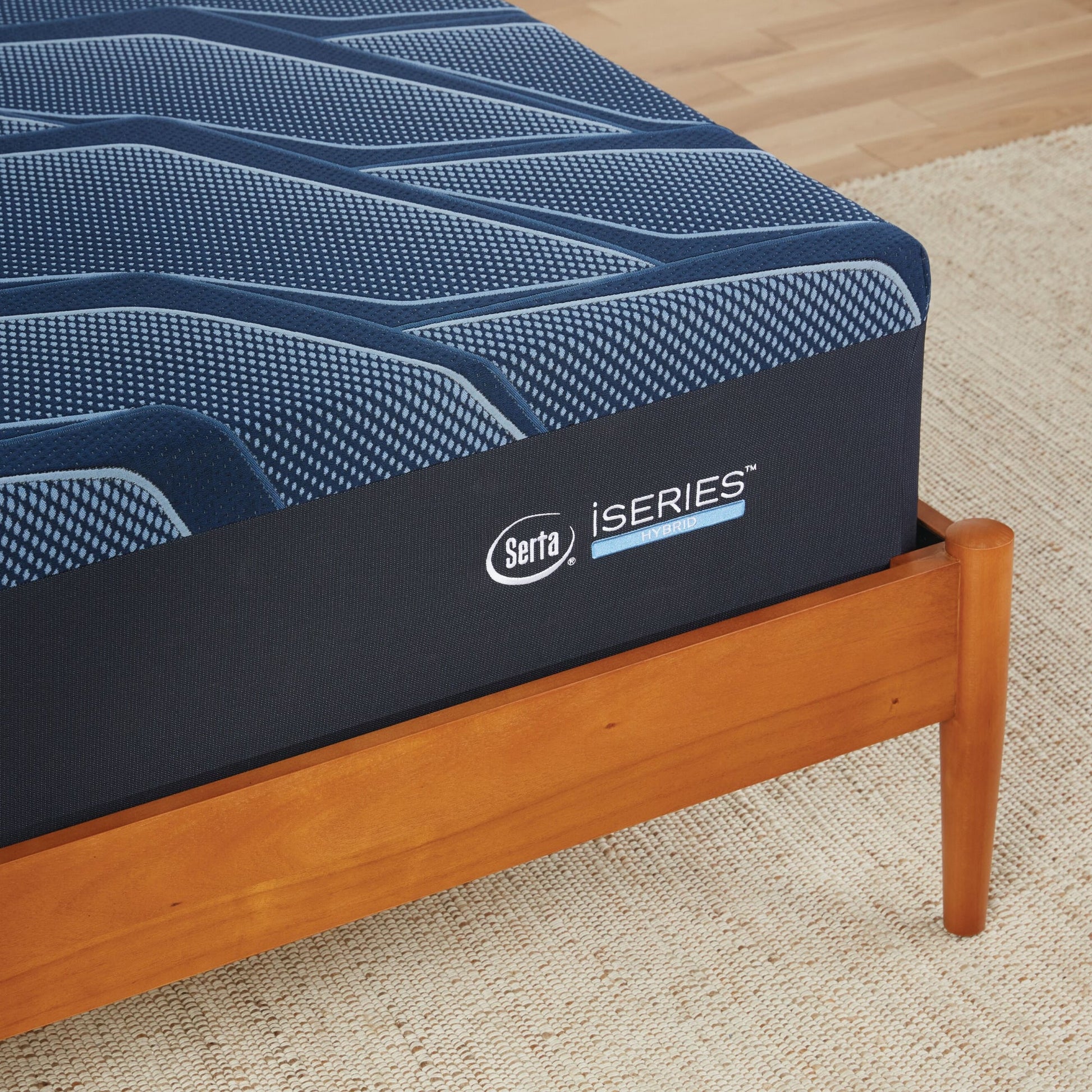 A corner of a wooden bed with a Serta iSeries plush blue mattress||feel: plush||level: Ultimate