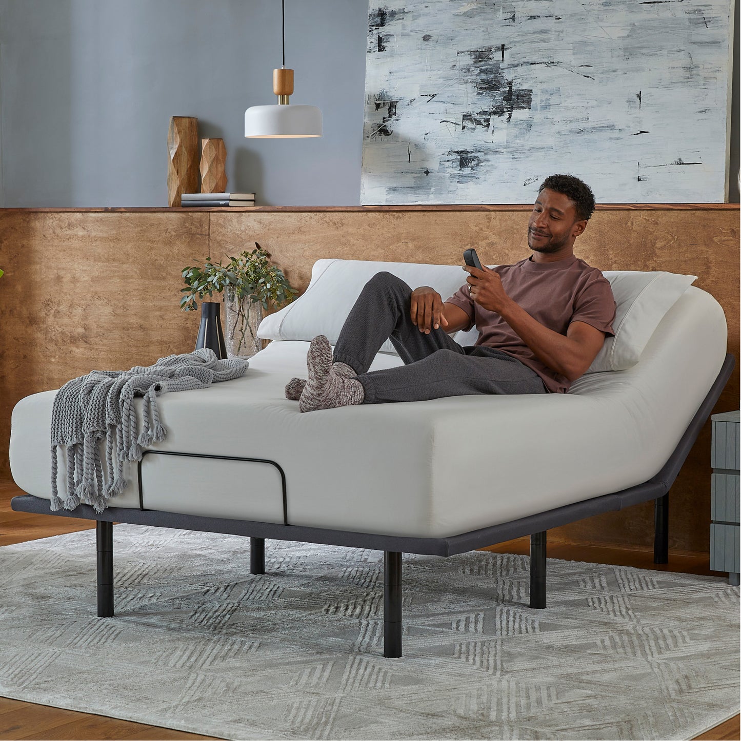 Man sitting in a Baselogic Silver Adjustable Base with a white mattress on top of it.