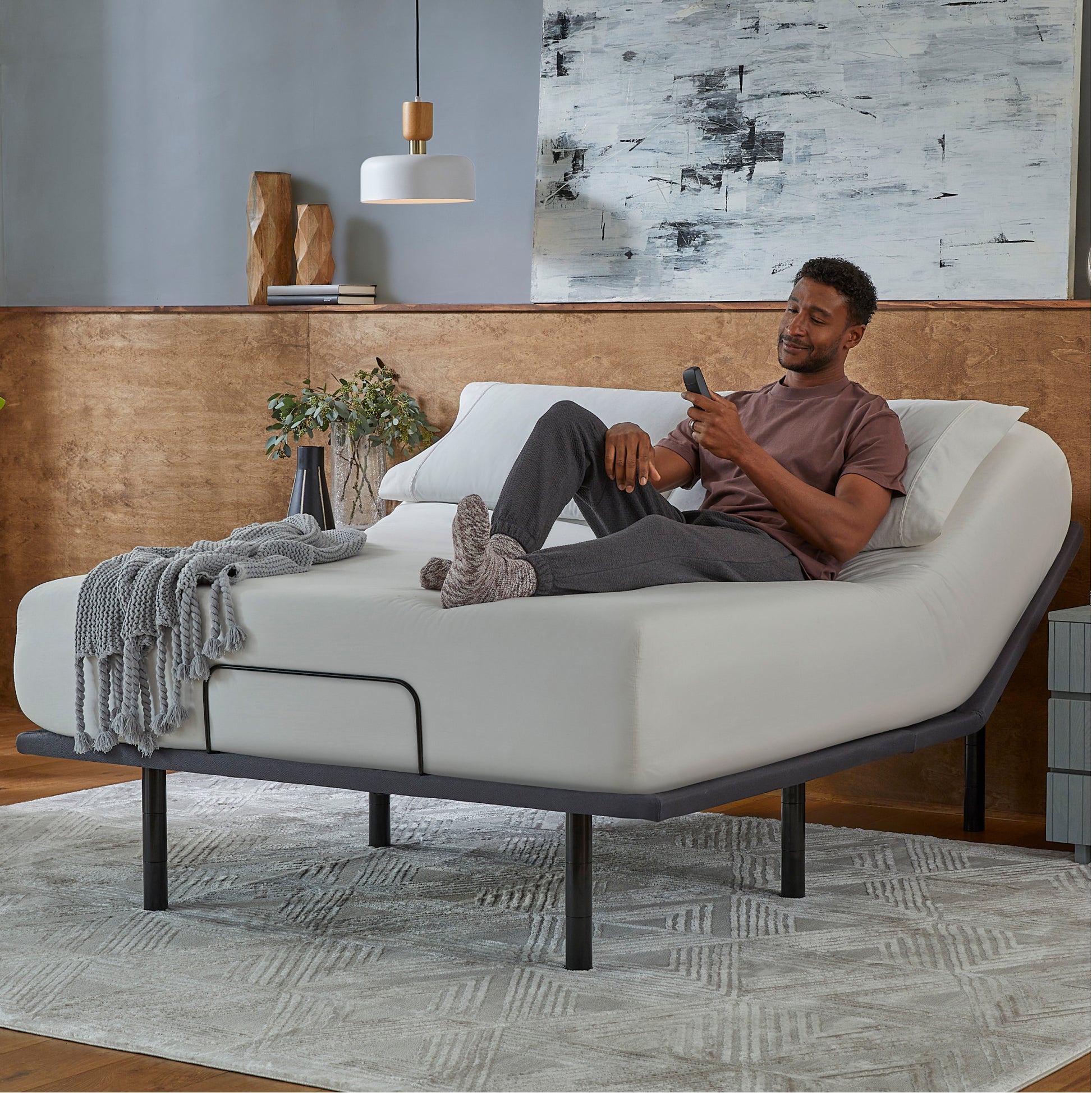 Man sitting in a Baselogic Silver Adjustable Base with a white mattress on top of it.