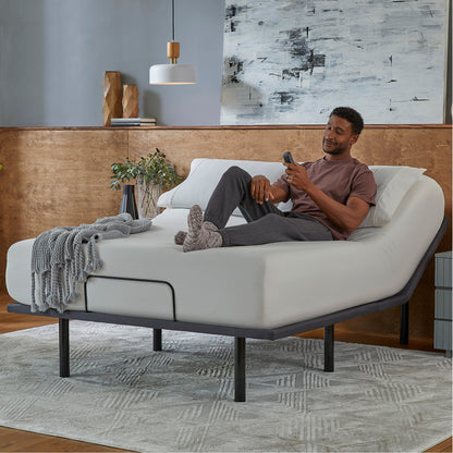 Man sitting in a Baselogic Silver Adjustable Base with a white mattress on top of it.