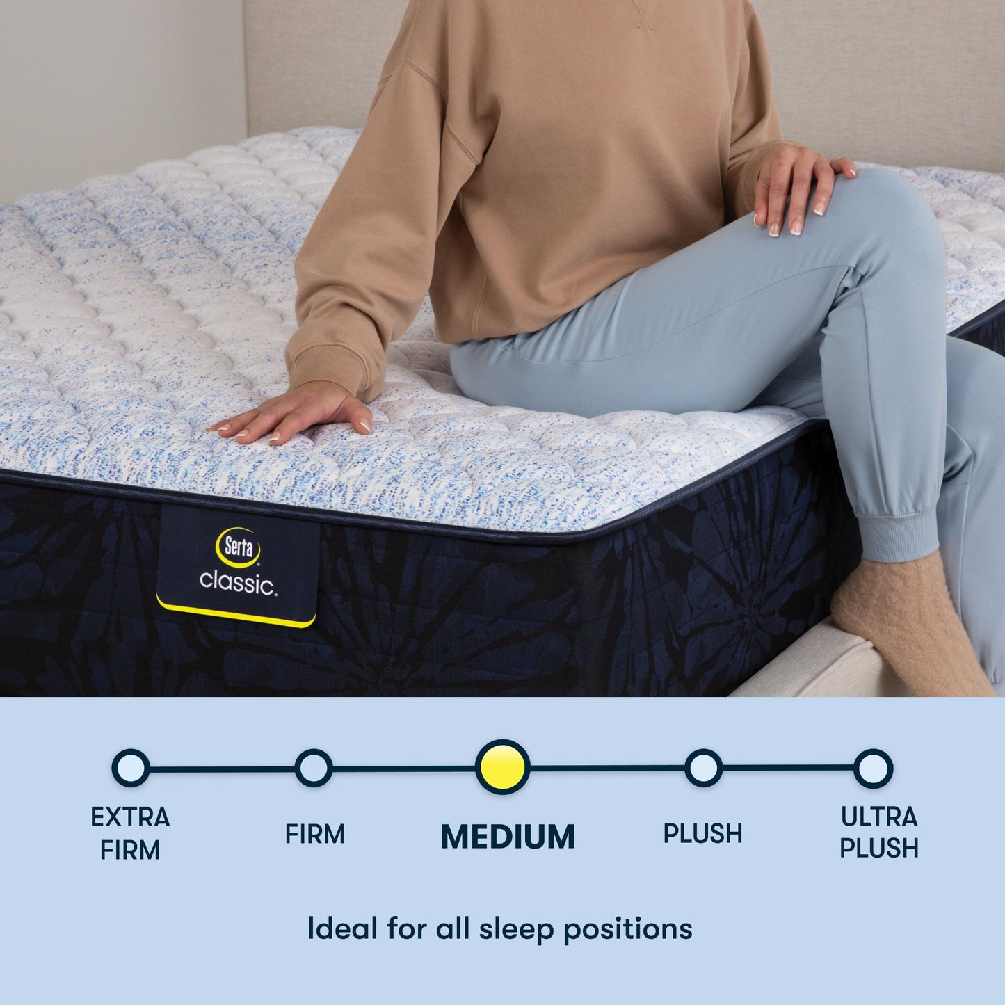 Woman sitting on a Serta classic medium mattress with her right hand placed on the mattress ||feel: medium ||level: standard