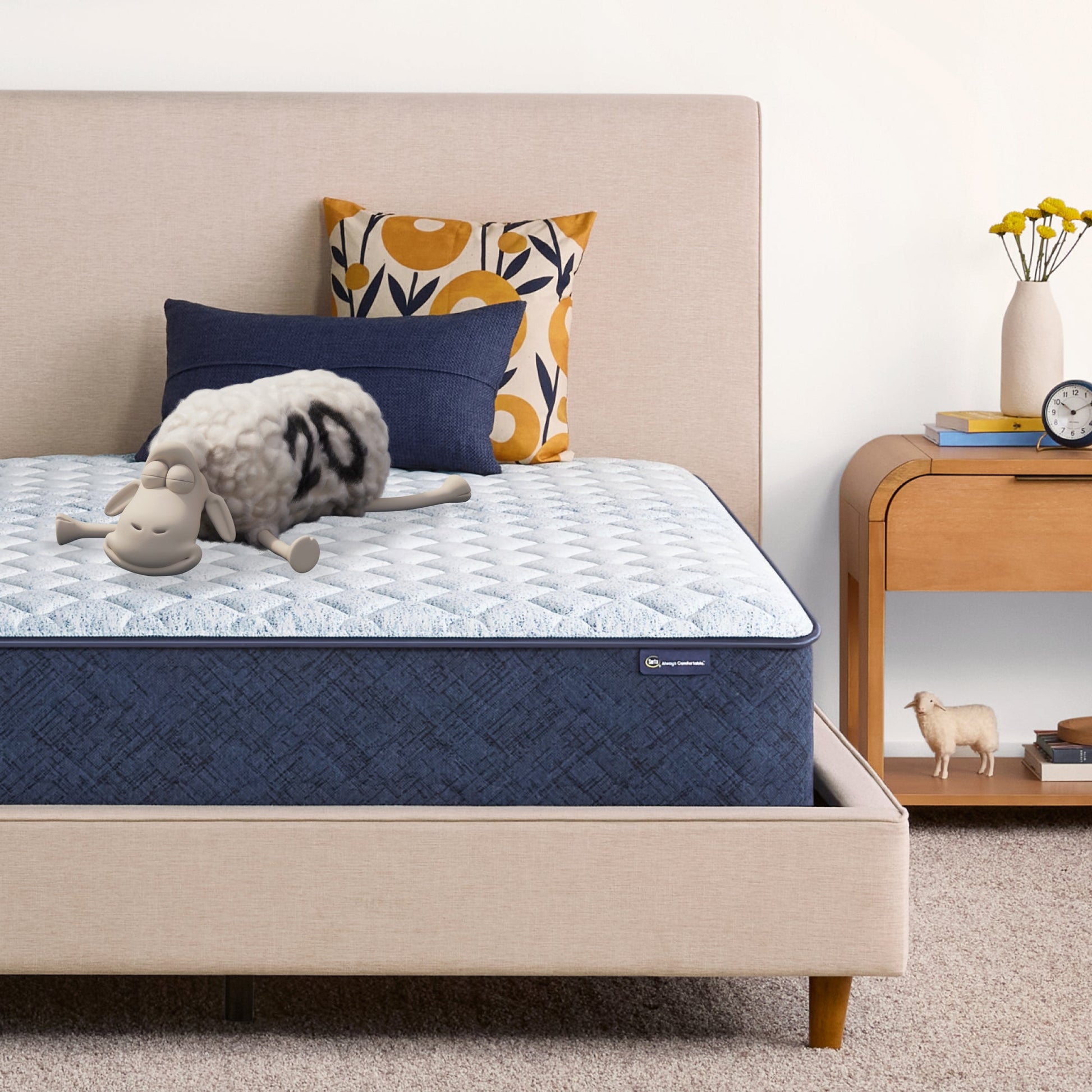 Sheep laying down with its eyes closed on an 11 inch hybrid mattress sitting in a beige bedframe || feel: Firm