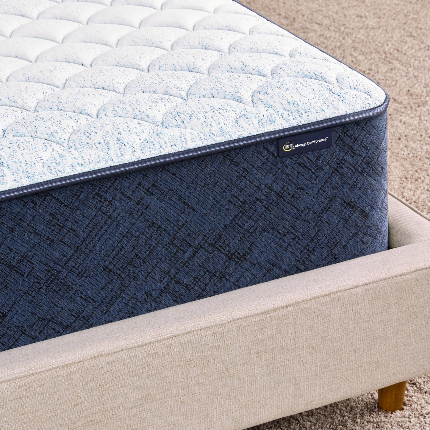 Corner of 12 inch foam mattress sitting in a beige bedframe || feel: Foam (12" Profile)