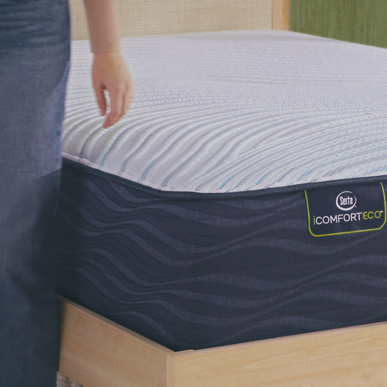 Person sitting on bed to to show firmness level of Serta iComforteco plush mattress||feel: plush || level: enhanced