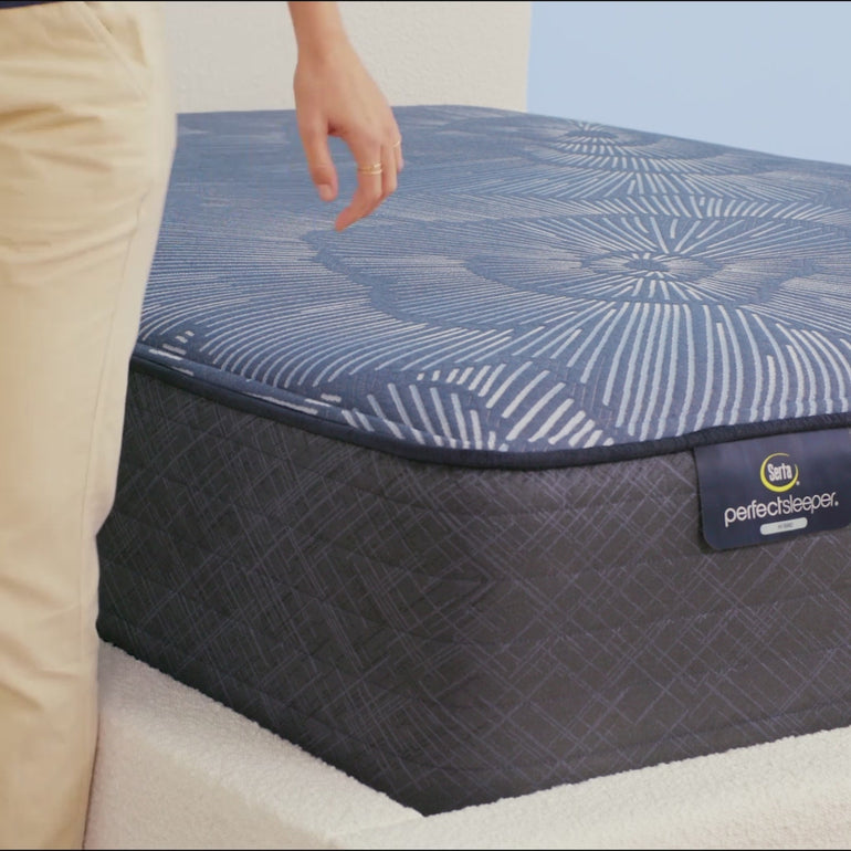 Person sitting on Serta Perfect Sleeper Hybrid plush mattress to show firmness||feel: plush||level: enhanced