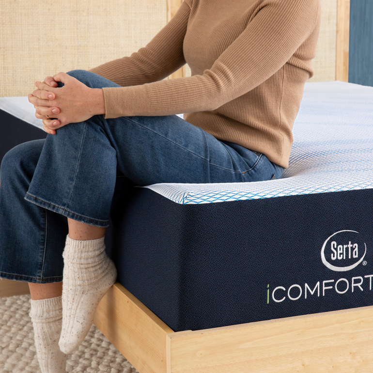 Person sitting on bed to showcase firmness level of Serta iComforteco mattress||feel: medium||level: standard