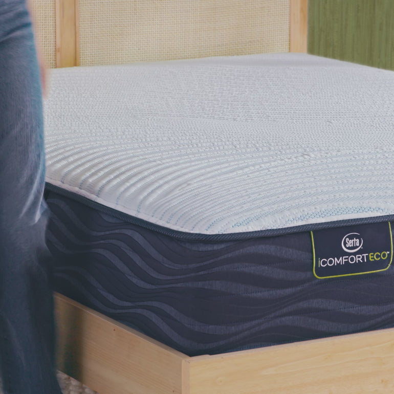 Person sitting on bed to to show firmness level of Serta iComforteco firm mattress|| feel: firm ||level: standard