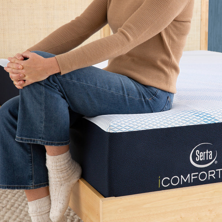Person sitting on bed to showcase firmness level of Serta iComforteco mattress||feel: firm||level: standard