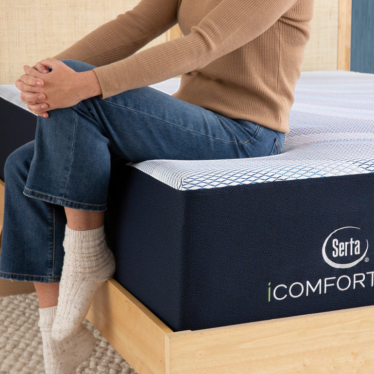 Person sitting on bed to showcase firmness level of Serta iComforteco mattress||feel: firm||level: enhanced