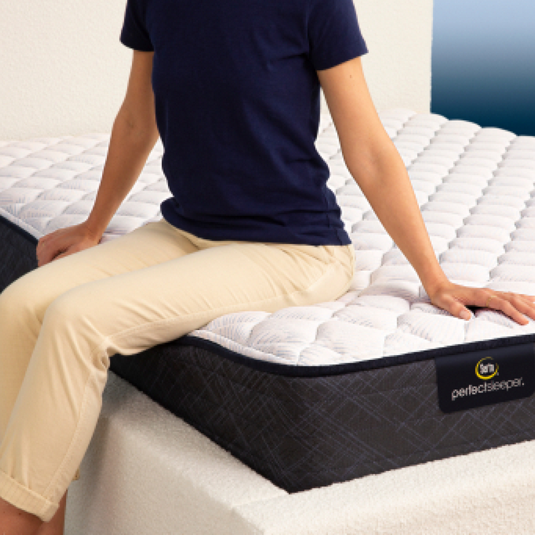 Person sitting on bed to show firmness level of Serta Perfect Sleeper firm mattress||feel: firm||level: standard