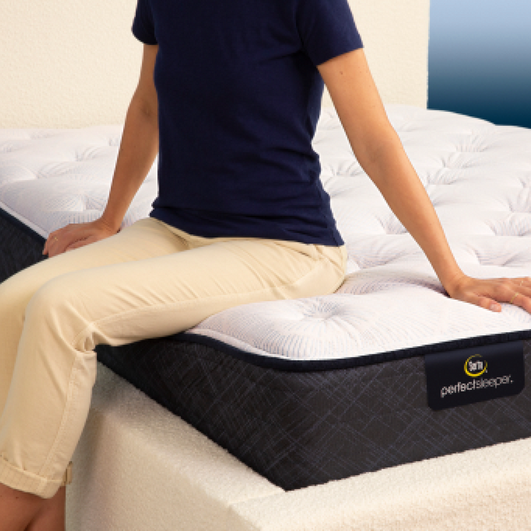 Person sitting on bed to show firmness level of Serta Perfect Sleeper plush mattress||feel: plush||level: standard
