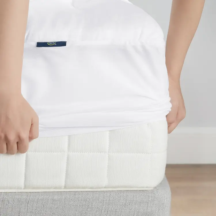 A person placing The Serta ComfortSure Mattress Pad over a mattress