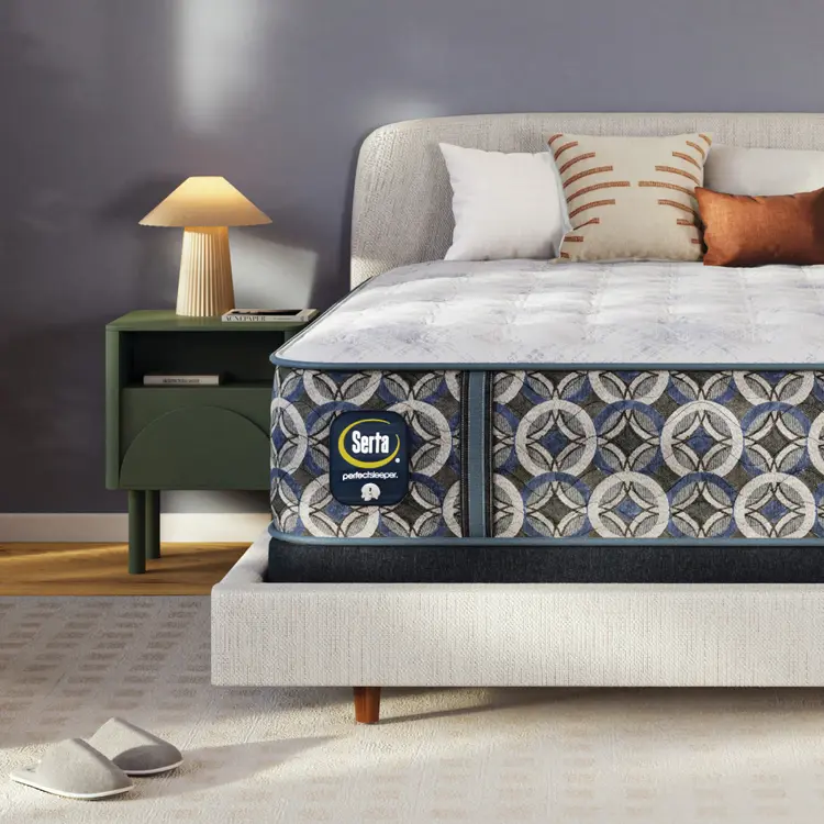 Serta perfect sleeper plush mattress on a bed in a bedroom setting with a nightstand and lamp.
