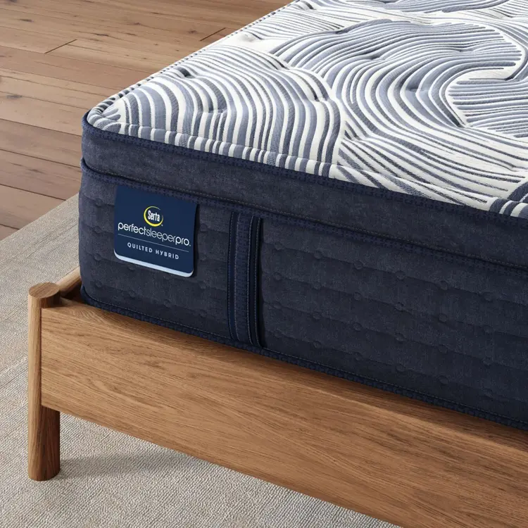 Corner of Perfect Sleeper Pro Edinburgh Plush Pillow Top mattress sitting in a brown bedframe || Level: Level 2 || Feel: Plush Pillow Top