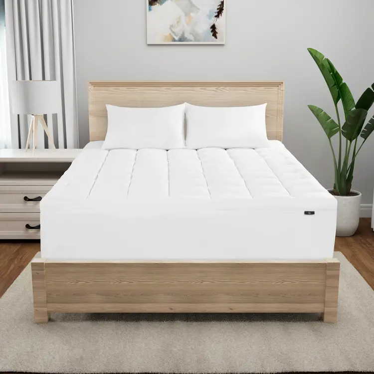 Serta Memory Flex Mattress Topper on top of a mattress in a brown bed frame with 2 pillows on top of it.