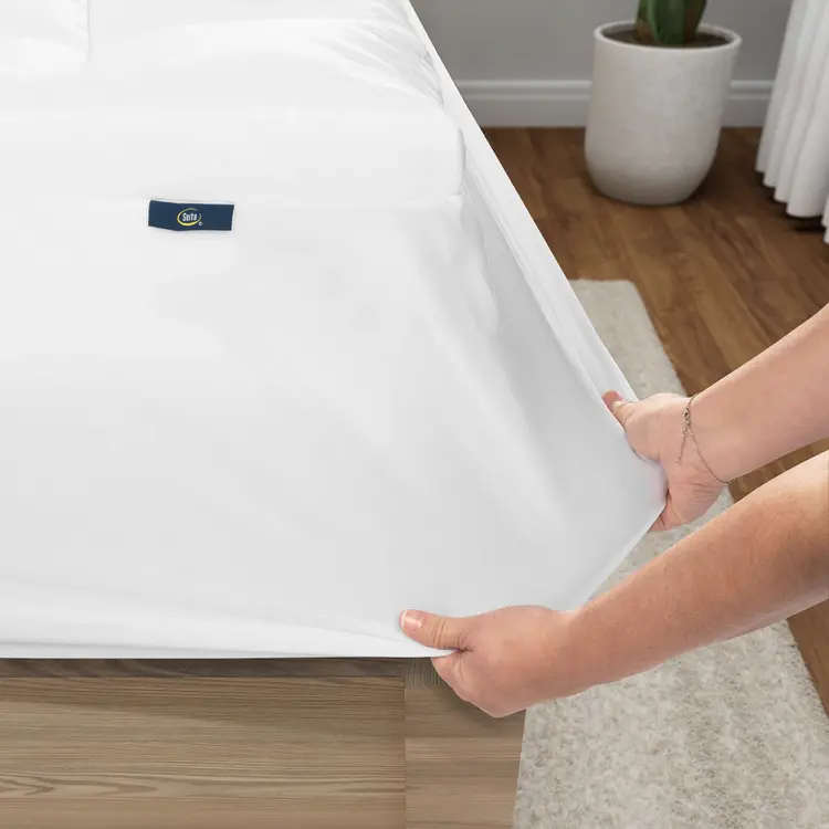 Serta Memory Flex Mattress Topper being stretched over a mattress by two hands