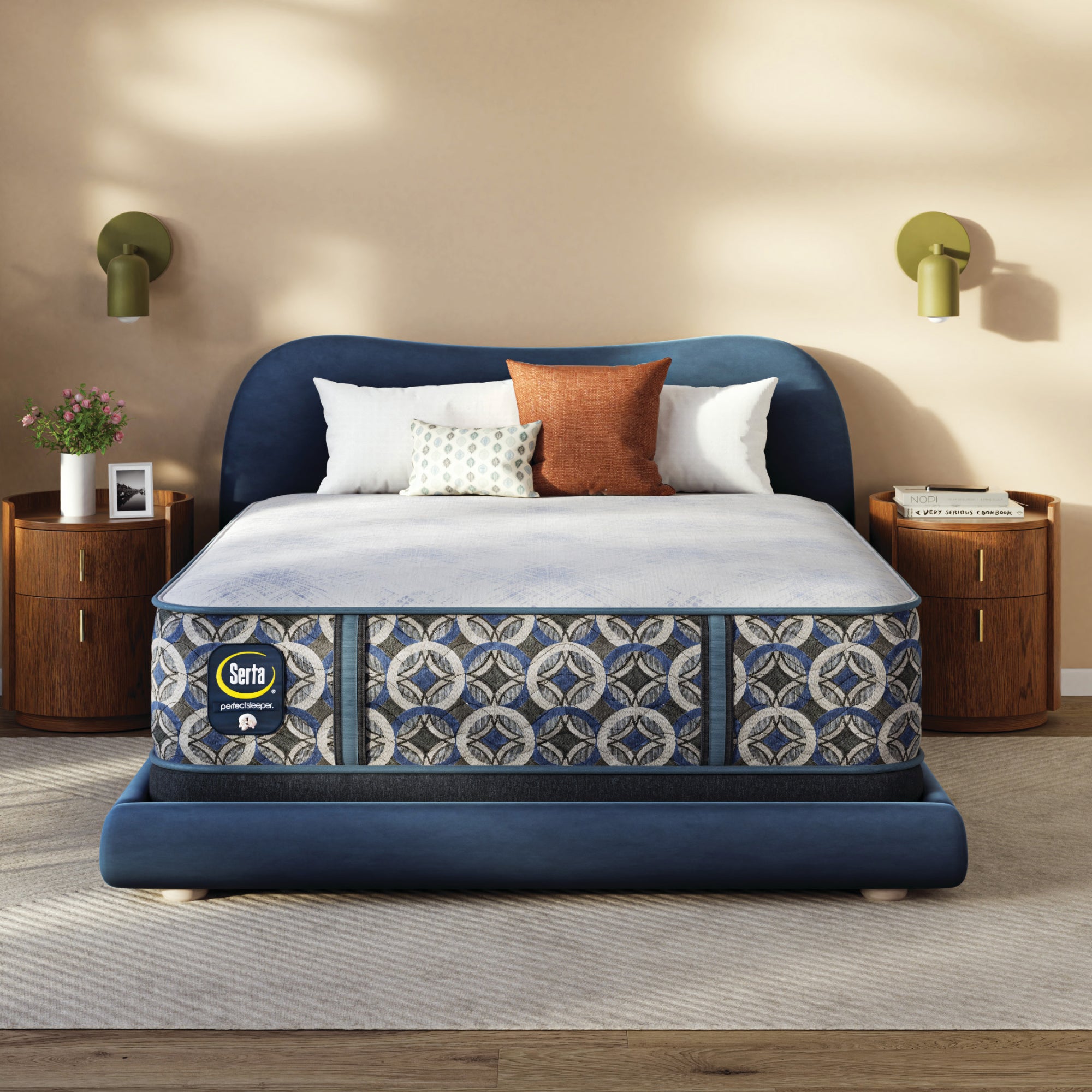 Blue upholstered bed with patterned Serta Perfect Sleeper Hybrid Firm mattress in a bedroom setting