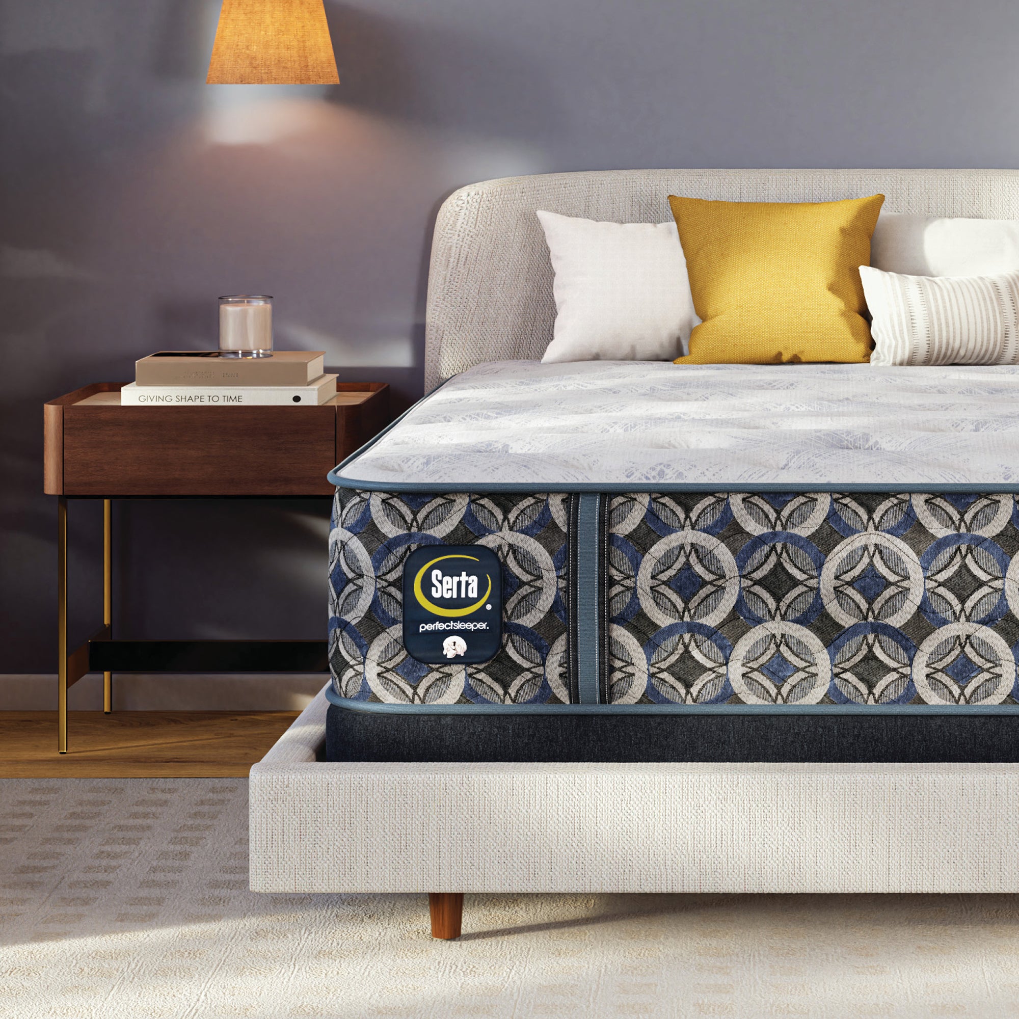 Serta perfect sleeper medium mattress on a bed with decorative pillows and a side table in a bedroom setting.